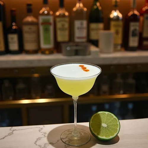 Pisco Sour cocktail with frothy egg white foam, garnished with Angostura bitters, in a glass.